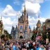 Crowds of visitors enjoying a sunny day at Walt Disney World Resort, with the iconic Cinderella Castle in the background